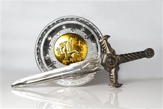 Silver and gold shield and sword against white background