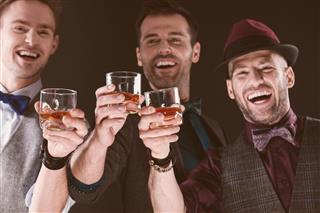 Happy elegant men toasting with whiskey