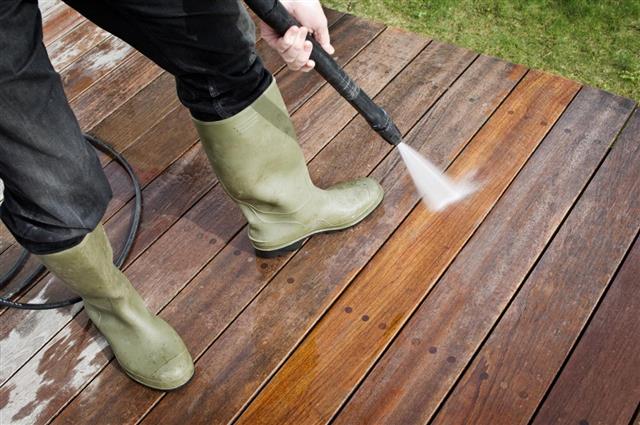 Man Cleaning Patio Decking With a Pressure Hose