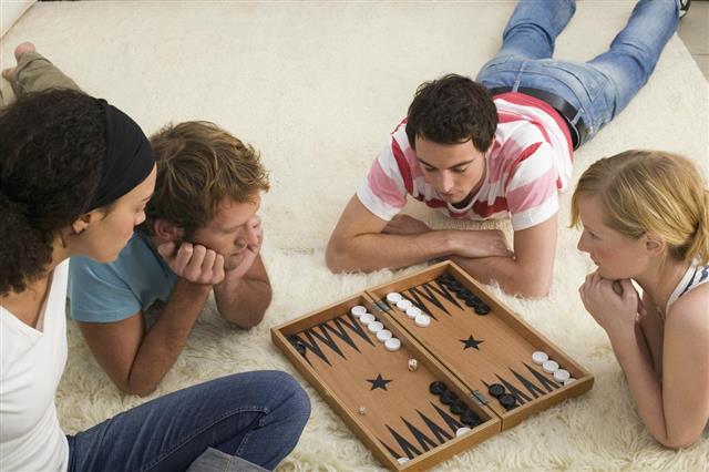 Four young people on floor playing Backgammon