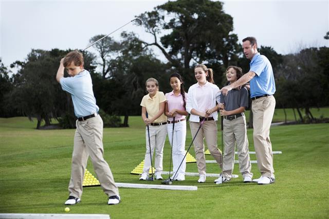 Golf pro with group of children on driving range
