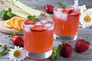 Lemonade with strawberries lemon and ice in a glass