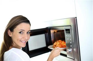 Woman putting a plate in microwave oven