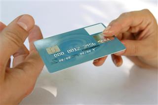 Hand passing a payment card (N.B. Mocked Up Details*)