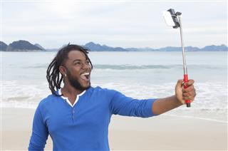 African guy with dreadlocks taking picture with selfie stick