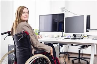 Woman sitting in wheelchair working in modern office