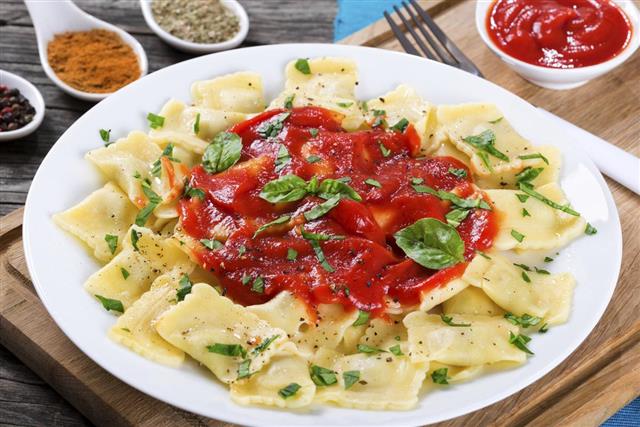 Ravioli with tomato sauce and basil leaves close-up