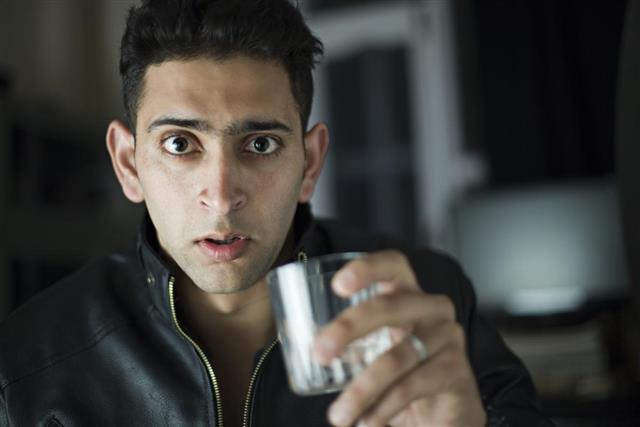 Shocked man holding a glass of water looking at camera
