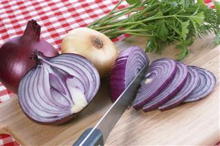 Chopped and whole red onions on a cutting board with a knife