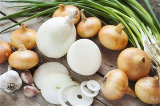 Different onions and garlic on wooden table