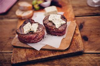 Tender steak medallions topped with cheese on wooden boards