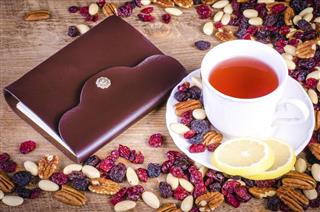 Dried fruits with white cup of tea saucer and notebook