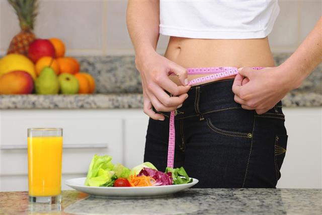 Diet: woman with salad and measuring tape