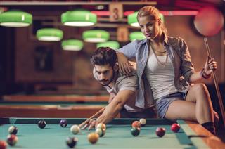Young couple playing snooker in a pool hall