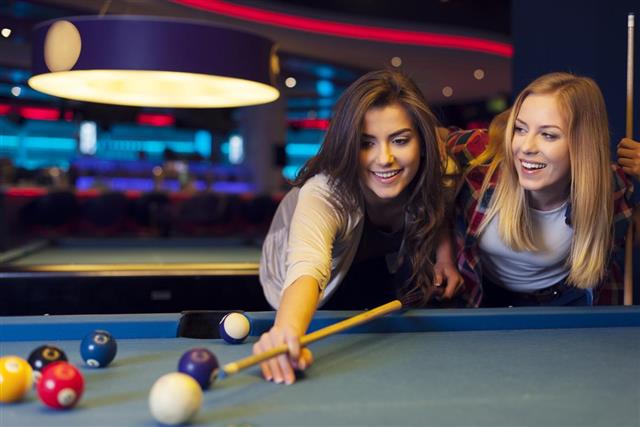 Two female friends enjoying pool game