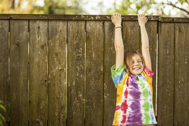 Color Young Girl in Tie Dyed T Shirt Dangling Fence