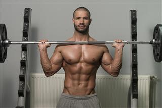 Bodybuilder Exercising Shoulders With Barbell