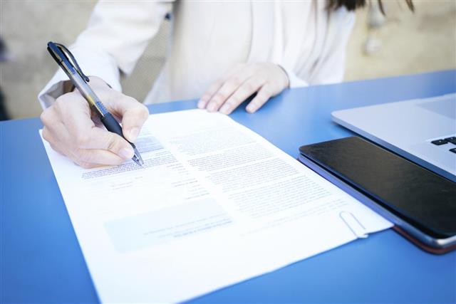 Businesswoman signs contract on blue table