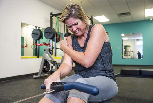 Injured middle-aged woman working out on a rowing machine