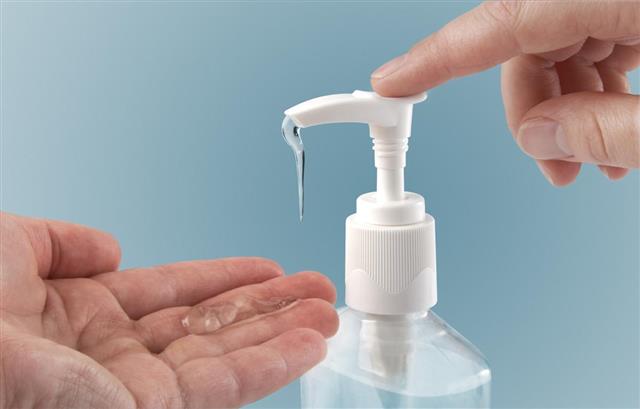 Photograph of a finger pumping sanitizer onto hand