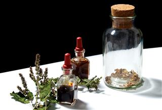 Three glass bottles with herbal extracts and patchouli branch