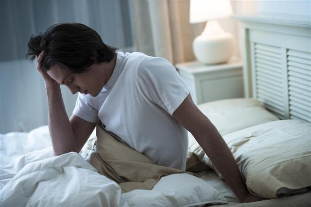 Man sitting in bed suffering from headache