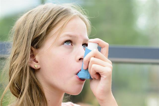 Pretty girl using asthma inhaler