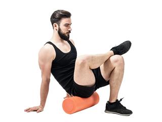 Athlete massaging glutes muscles with foam roller