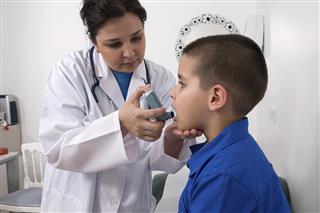Doctor helping a boy with his asthma inhaler