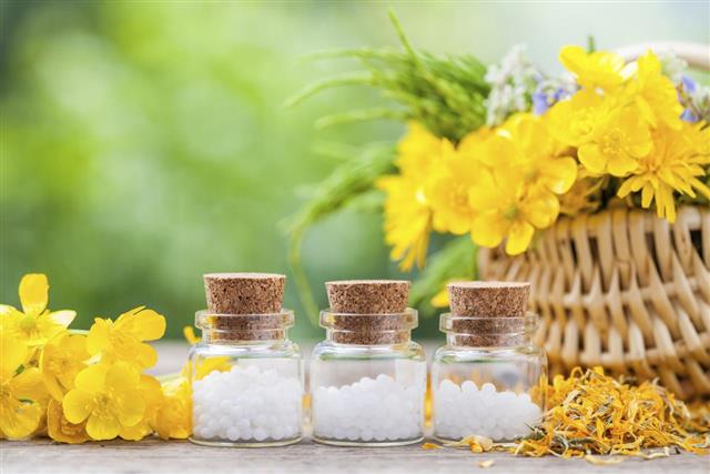 Bottles of homeopathy globules and healthy herbs in basket