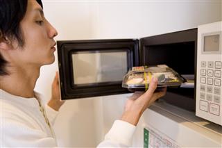 Man putting boxed lunch into microwave