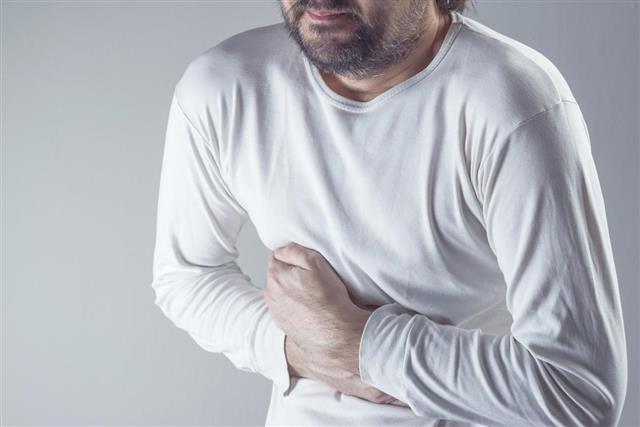 Man suffering from severe abdominal pain hands on stomach