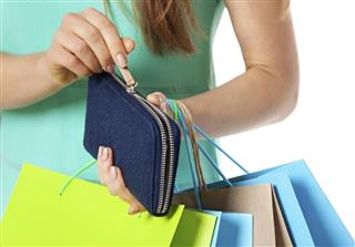 Closeup of womans hand with shopping bags opening wallet