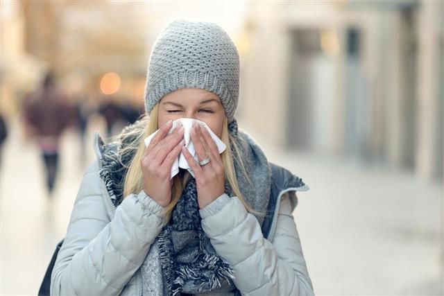 Woman with a seasonal winter cold blowing her nose