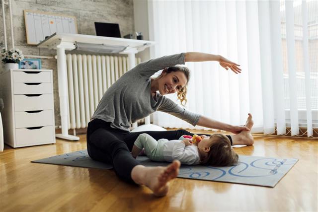 Mother Exercise With Her Baby At Home