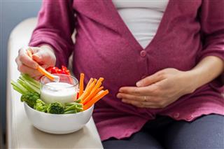 Pregnant woman eating vegetable sticks