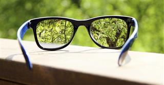 Eyeglasses in the hand over blurred tree background