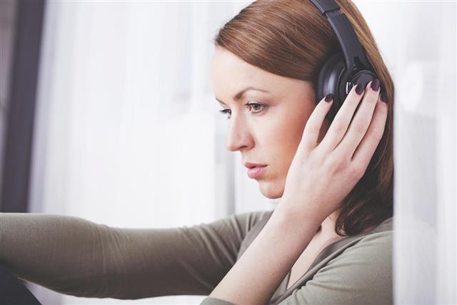 Pensive brown haired girl sitting listening to music