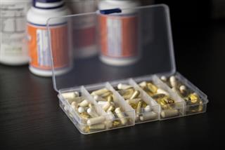 Supplements into daily pill box in front of bottles