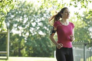 Female Runner In Park With Wearable Technology
