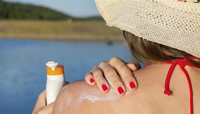 Young woman putting sun lotion on summer vacation