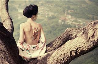 Woman with snake tattoo on the tree branch