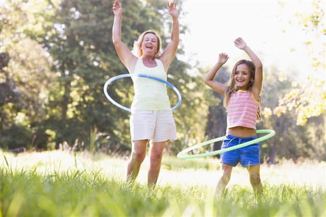 Grandmother and granddaughter hula hooping in park