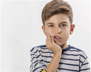 Boy having a toothache holding his face with his hand