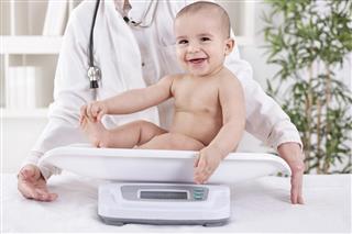 Happy smiling baby in pedrician office measuring weight