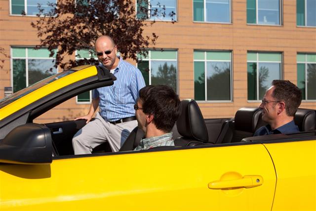 Three men car pooling in a yellow convertible
