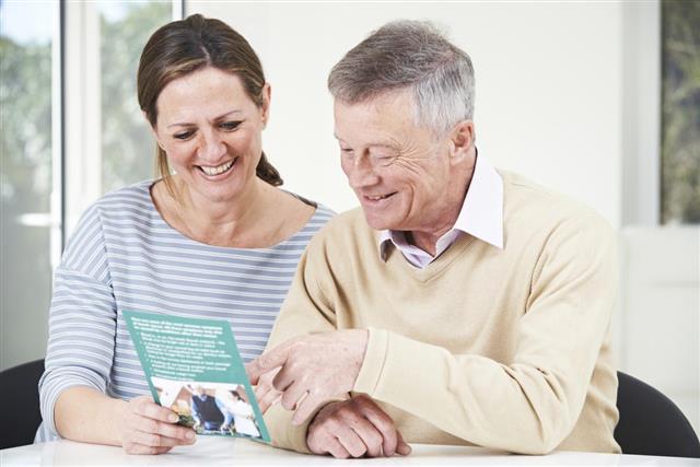 Senior Man With Adult Daughter Looking At Brochure For Retiremen