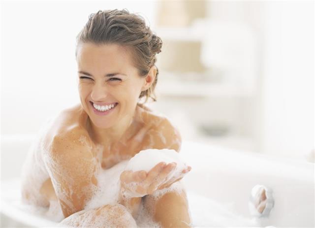 Young woman playing with foam in bathtub