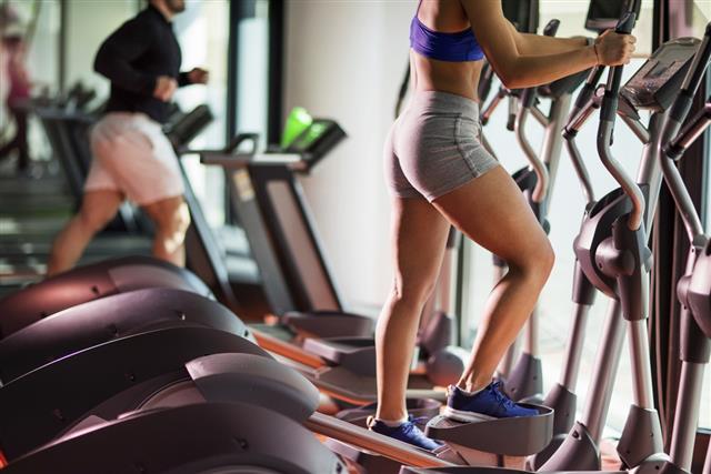 Unrecognizable woman exercising on stair climbing machine in a gym