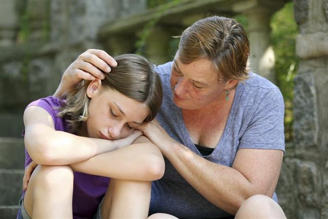 Mother giving comfort to teenage daughter